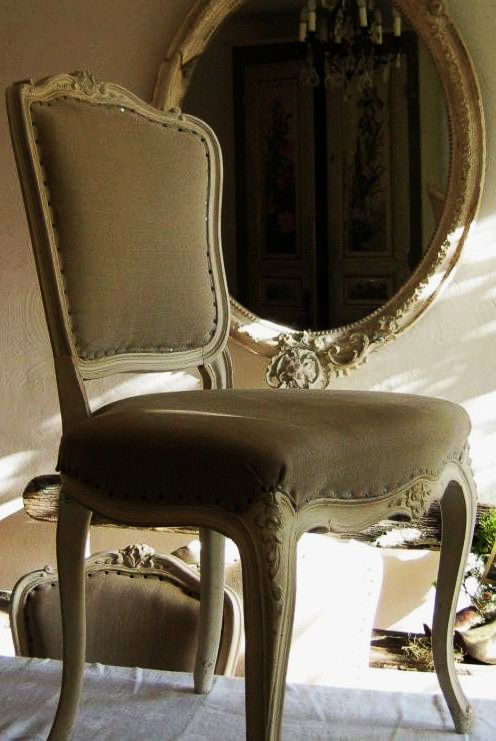 An antique chairs sits on the table looking at itself in the mirror